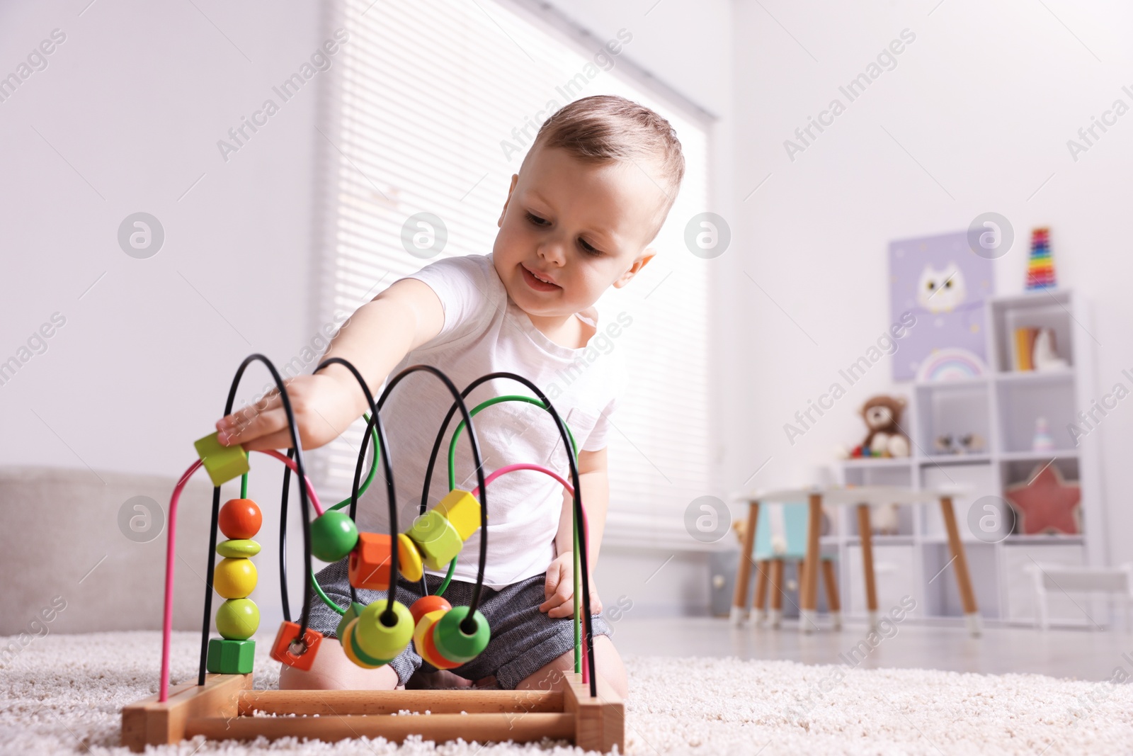 Photo of Motor skills development. Little boy playing with toy on floor at home, space for text