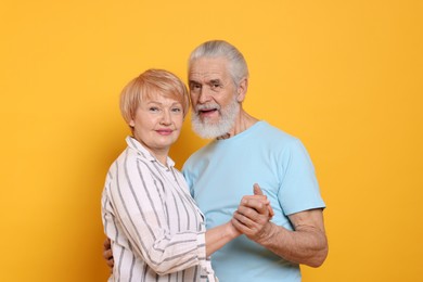 Photo of Portrait of lovely senior couple holding hands on orange background