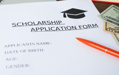 Photo of Scholarship application form, pen and dollar banknotes on table, closeup