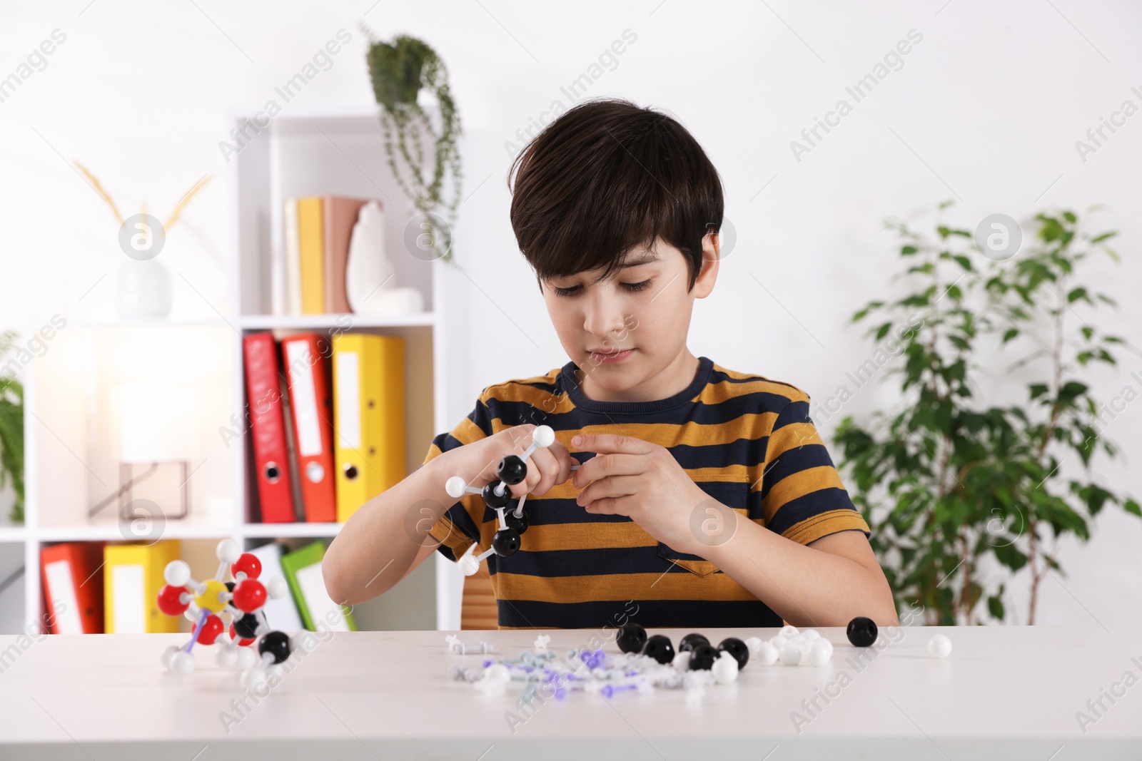 Photo of Boy making DNA structure model at desk indoors