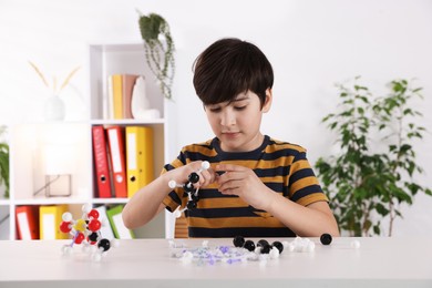 Photo of Boy making DNA structure model at desk indoors