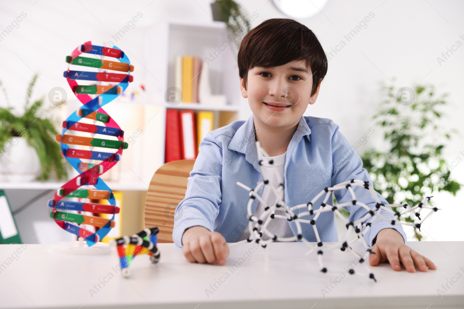 Photo of Boy with DNA structure model at desk indoors