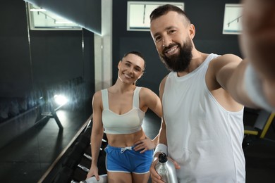 Photo of Couple with water bottles taking selfie after training in gym