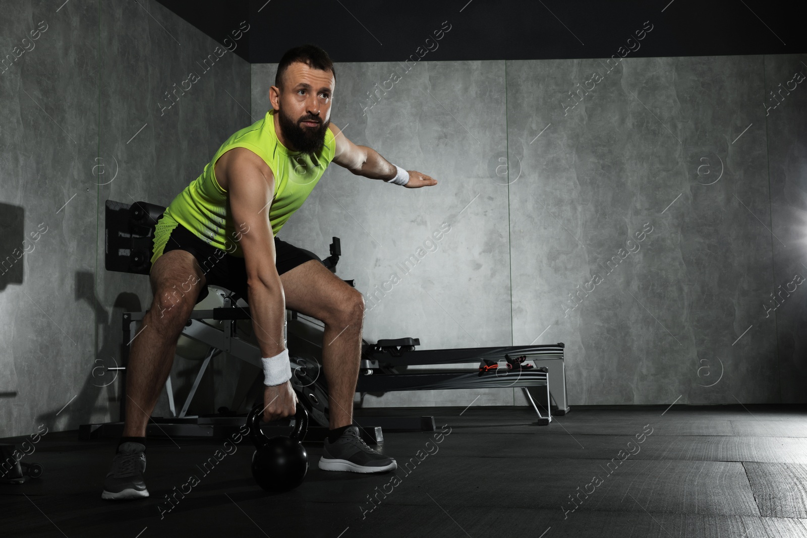 Photo of Athletic man training with kettlebell in gym. Space for text