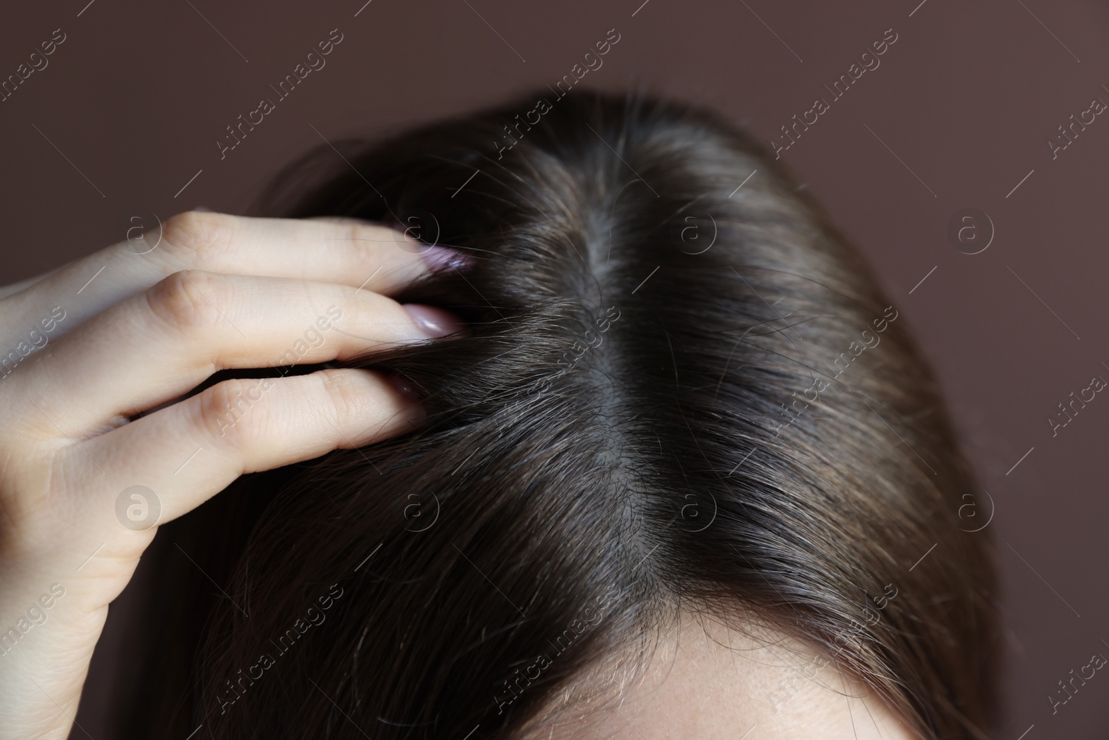 Photo of Woman with healthy hair roots on brown background, closeup