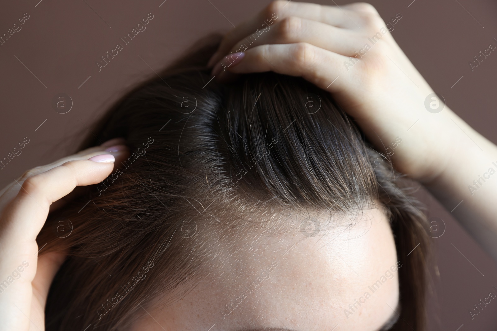 Photo of Woman with healthy hair roots on brown background, closeup