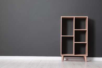 Photo of Empty shelving unit near grey wall indoors, space for text