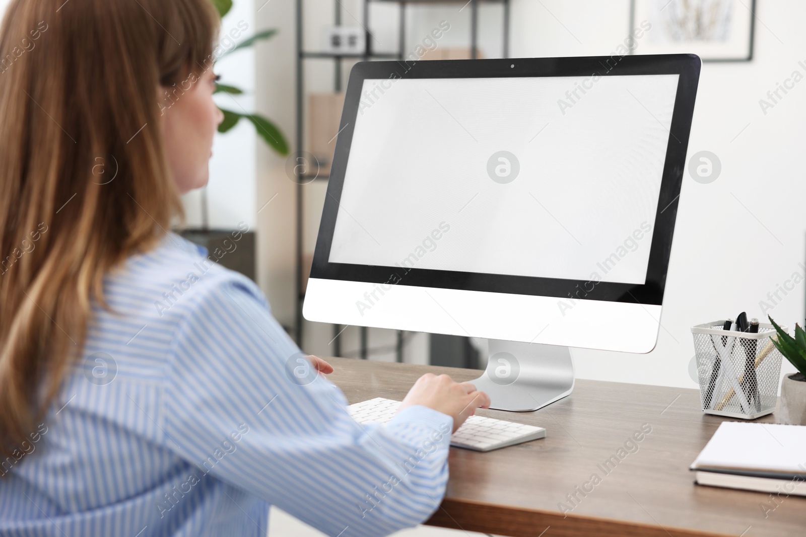 Photo of Woman working on computer at wooden desk in office. Mockup for design