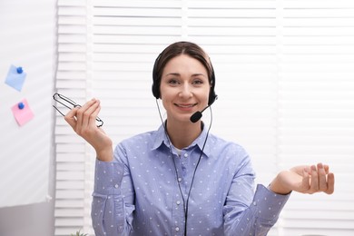 Photo of Smiling online speaker in headset streaming webinar indoors, view from web camera