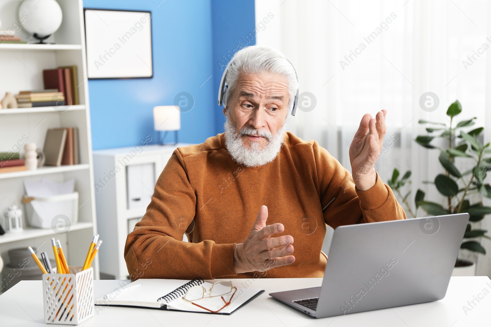 Photo of Senior man having online lesson with teacher at desk indoors. Self-study