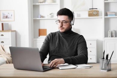 Photo of Man learning online using laptop at desk indoors. Self-study