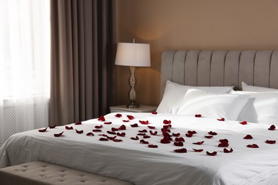 Photo of Many beautiful rose petals on bed indoors