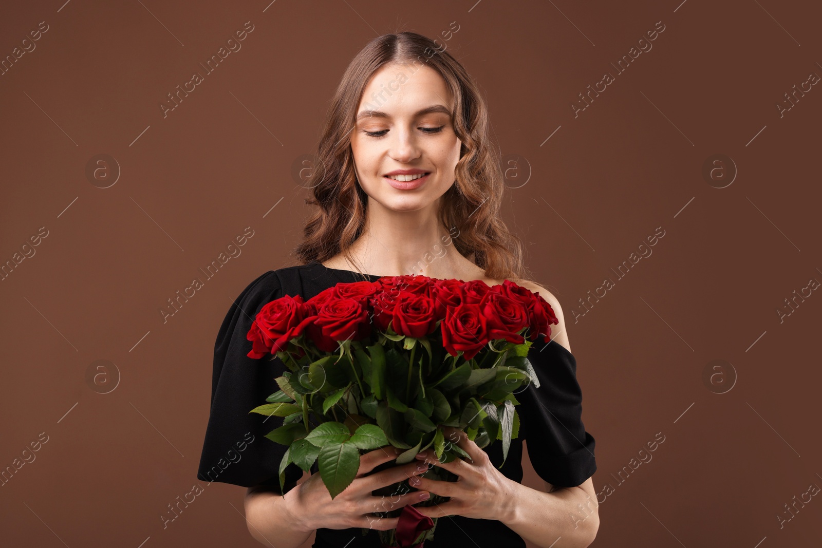 Photo of Smiling woman with bouquet of roses on brown background