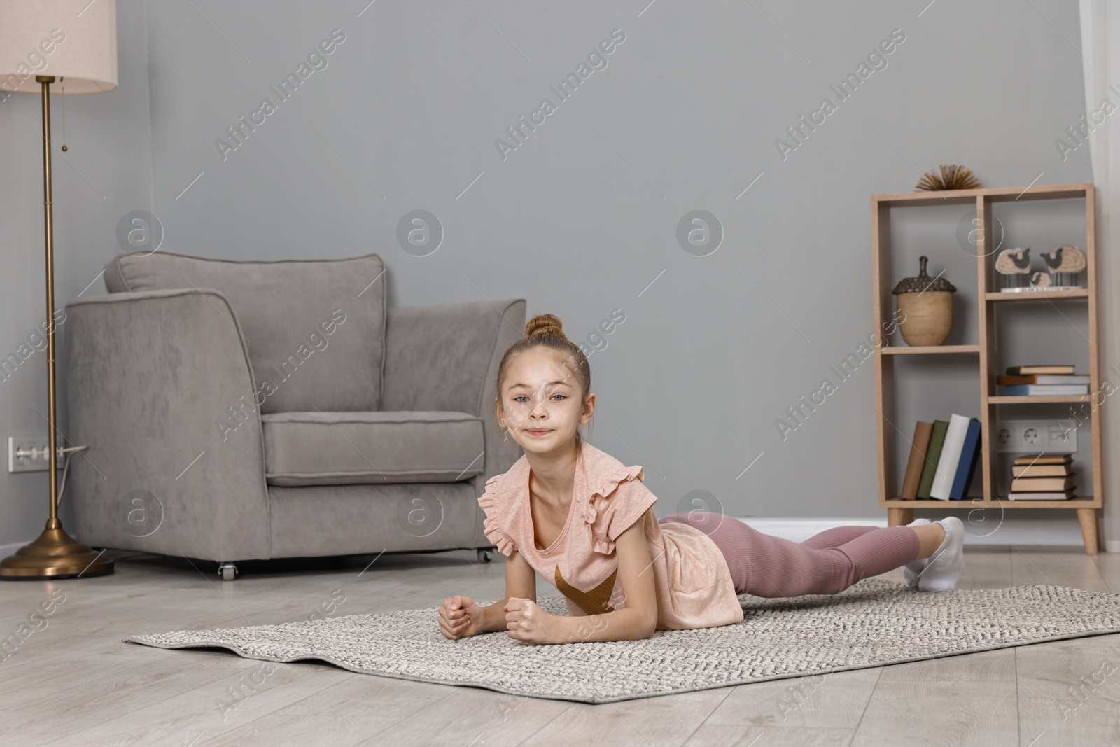 Photo of Little girl doing plank exercise at home. Morning routine