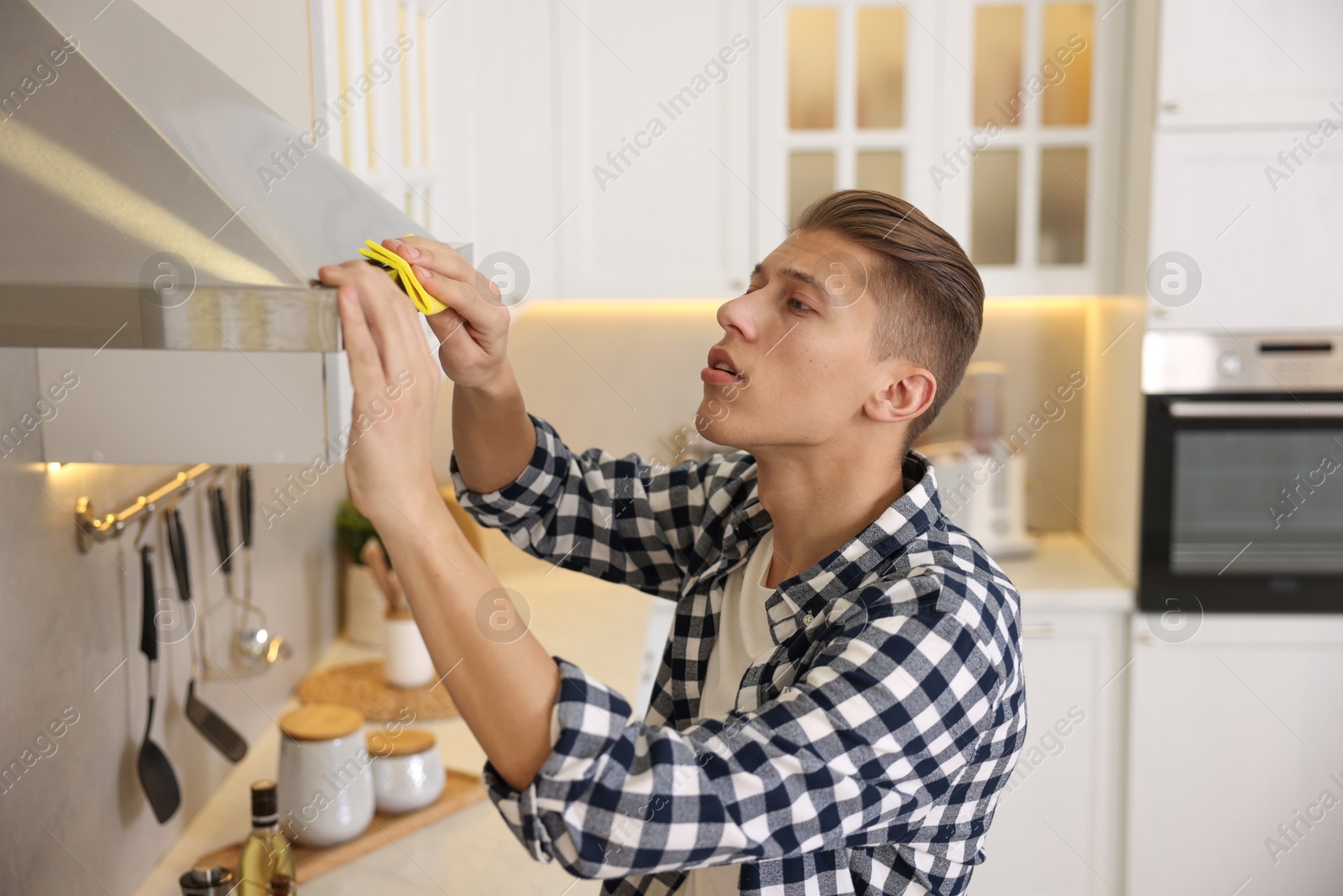 Photo of Man cleaning kitchen hood with rag at home