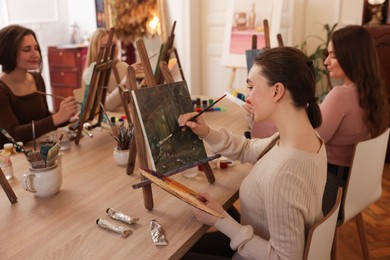 Photo of Group of women learning to draw at wooden table in class