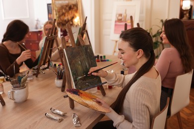 Photo of Group of women learning to draw at wooden table in class