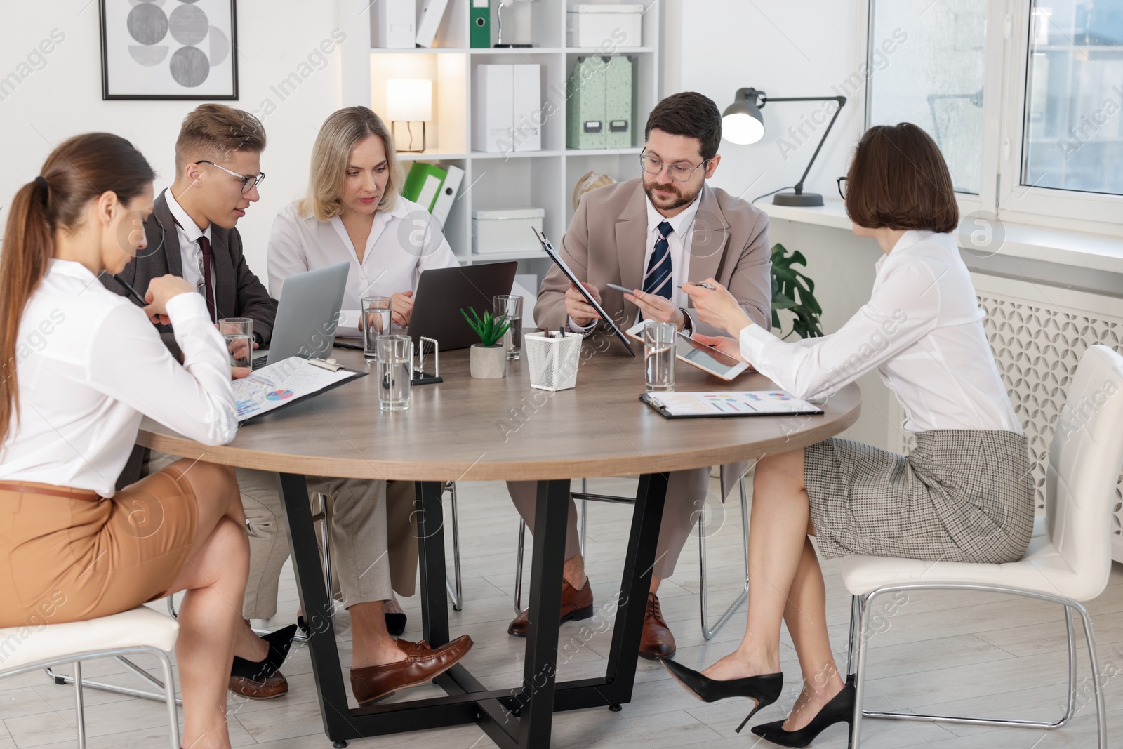 Photo of Coworkers working together at wooden table in office