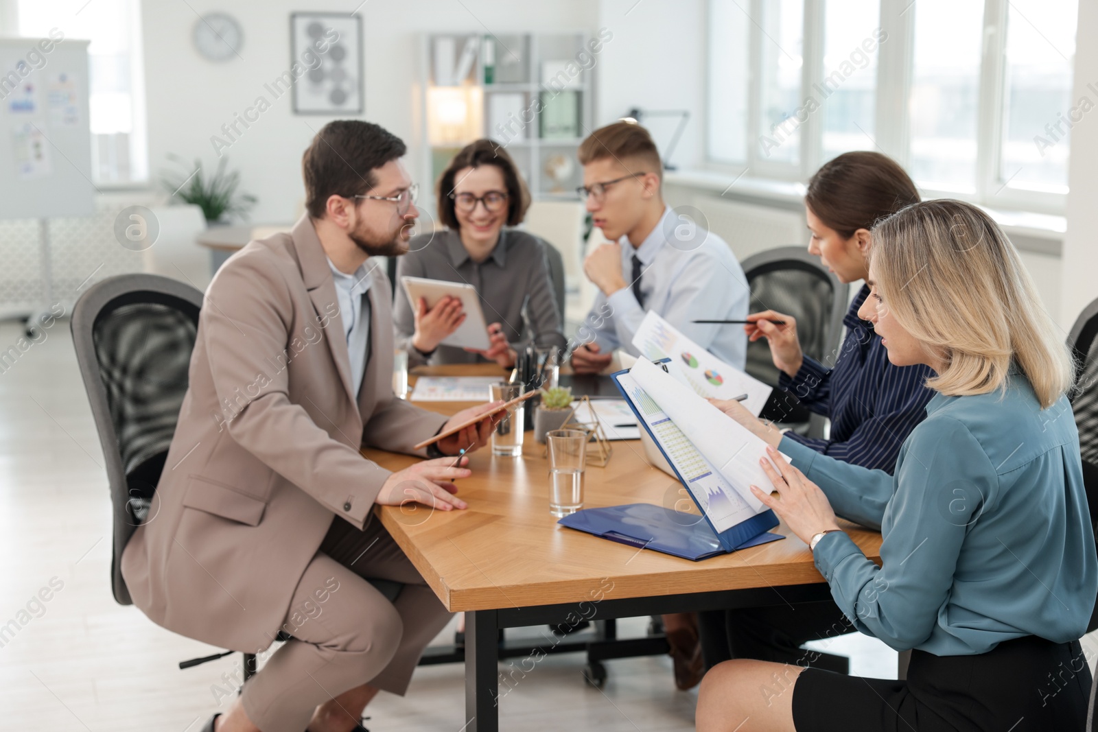 Photo of Coworkers working together at wooden table in office