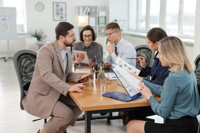 Photo of Coworkers working together at wooden table in office