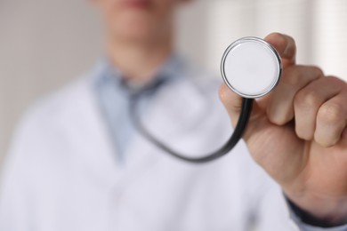 Photo of Doctor with stethoscope on light background, closeup