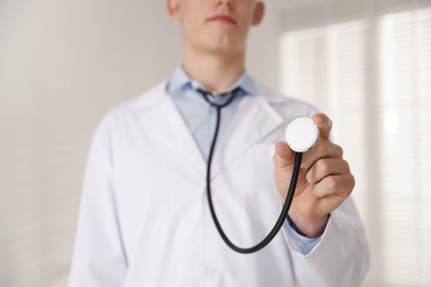 Photo of Doctor with stethoscope on light background, closeup