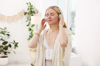 Photo of Feng shui. Young woman with headphones listening to music at home