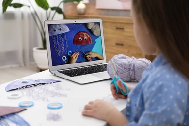 Photo of Little girl making handmade jellyfish by craft tutorial video at home, selective focus. Child creativity