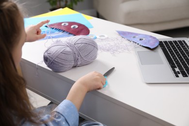 Photo of Little girl making handmade jellyfish by craft tutorial video at white table. Child creativity