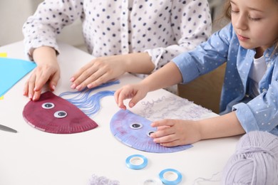 Photo of Woman and little girl making paper jellyfish at home, closeup. Child handmade craft