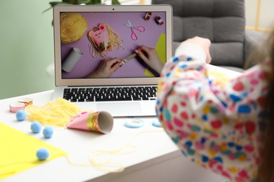 Photo of Little girl making handmade toy by following craft tutorial video at home. Child creativity