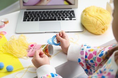 Photo of Little girl making handmade toy by following craft tutorial video at home. Child creativity