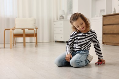 Photo of Little girl playing with toy car on floor at home, space for text