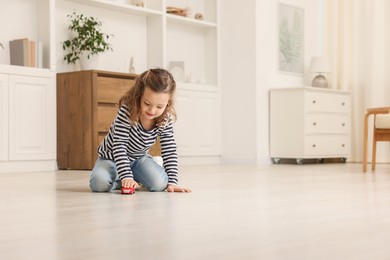 Photo of Little girl playing with toy car on floor at home, space for text