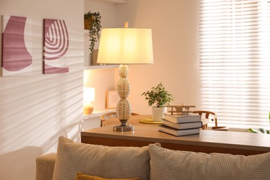 Photo of Beautiful night lamp, stack of books and airplane model on chest of drawers indoors