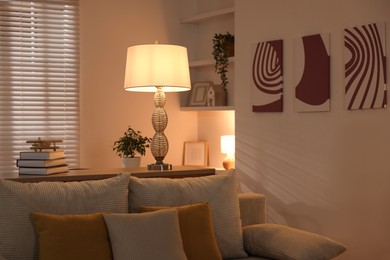 Photo of Beautiful night lamp, stack of books and airplane model on chest of drawers indoors