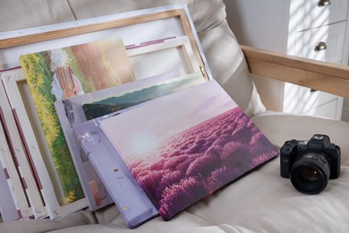 Photo of Canvas with different printed photos and camera on sofa indoors