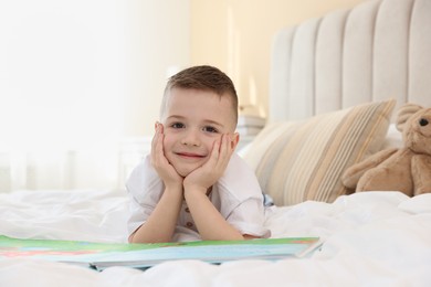 Photo of Bedtime. Cute boy with book on bed indoors