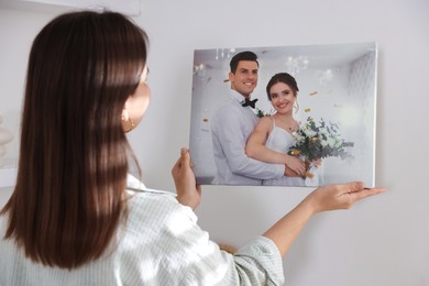 Photo of Canvas print. Woman hanging photo on wall at home