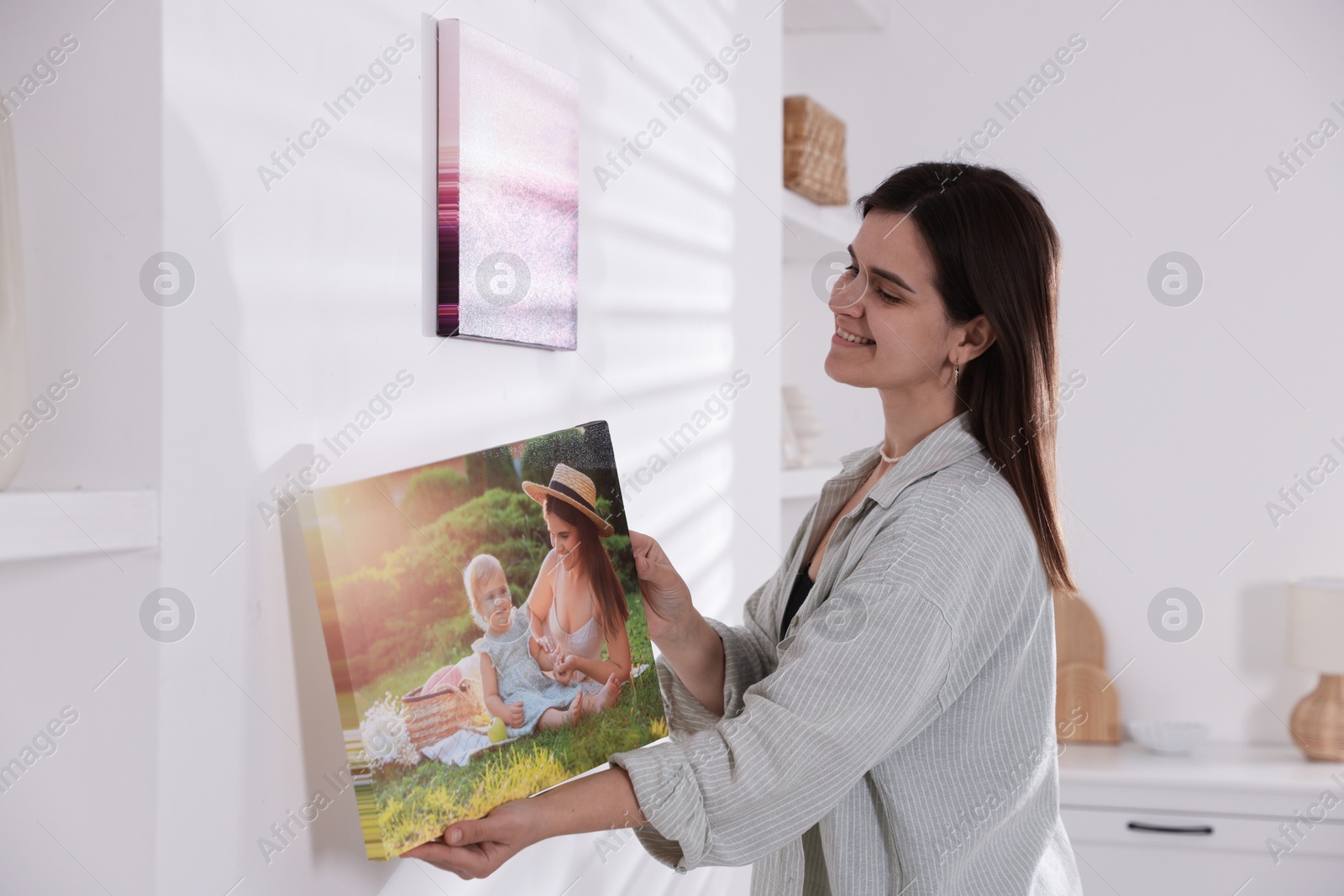 Photo of Canvas print. Woman hanging photo on wall at home