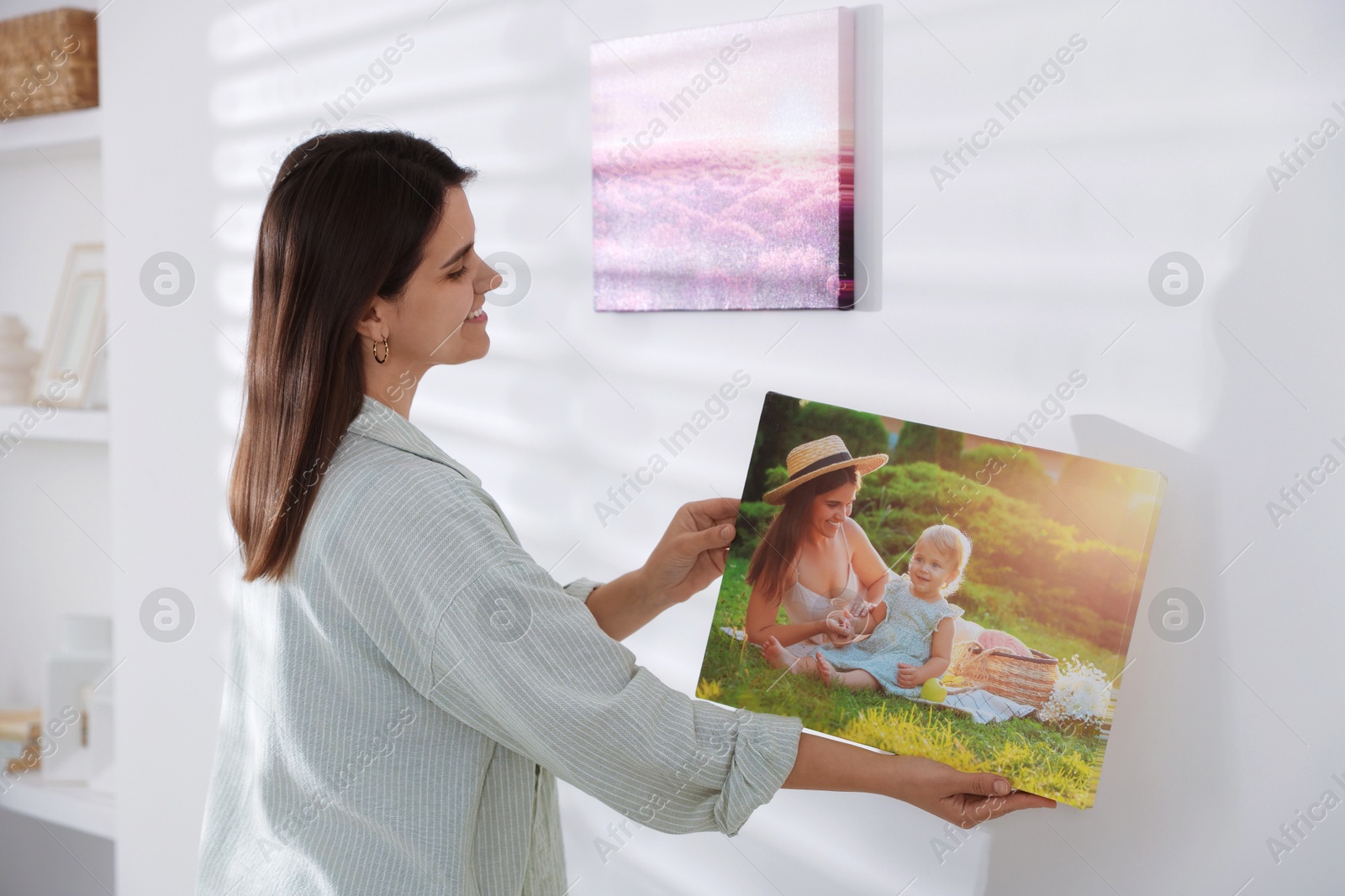 Photo of Canvas print. Woman hanging photo on wall at home