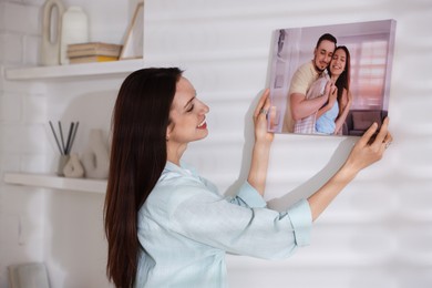 Photo of Canvas print. Woman hanging photo on wall at home