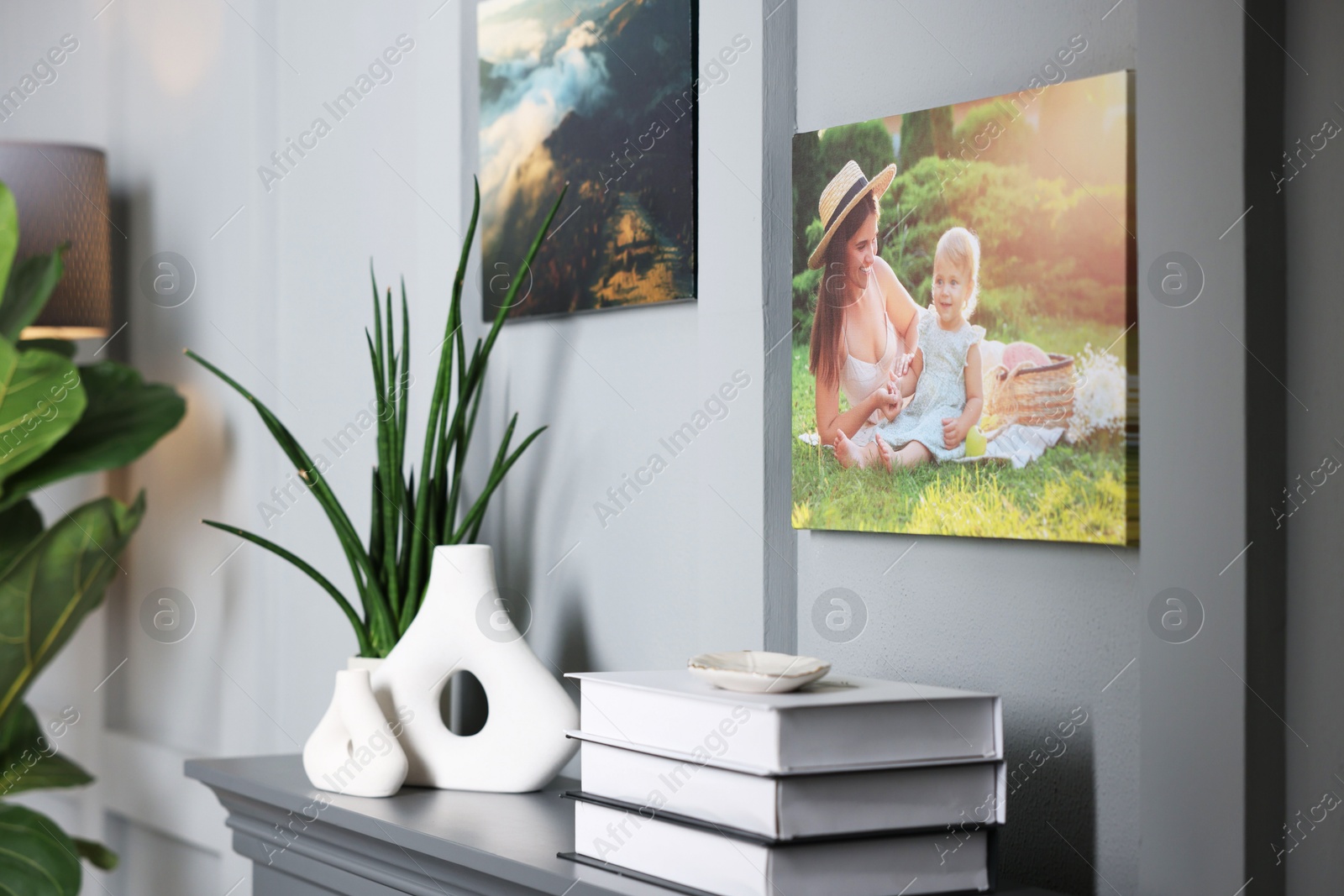 Photo of Canvas with printed photos on wall over decorative fireplace indoors