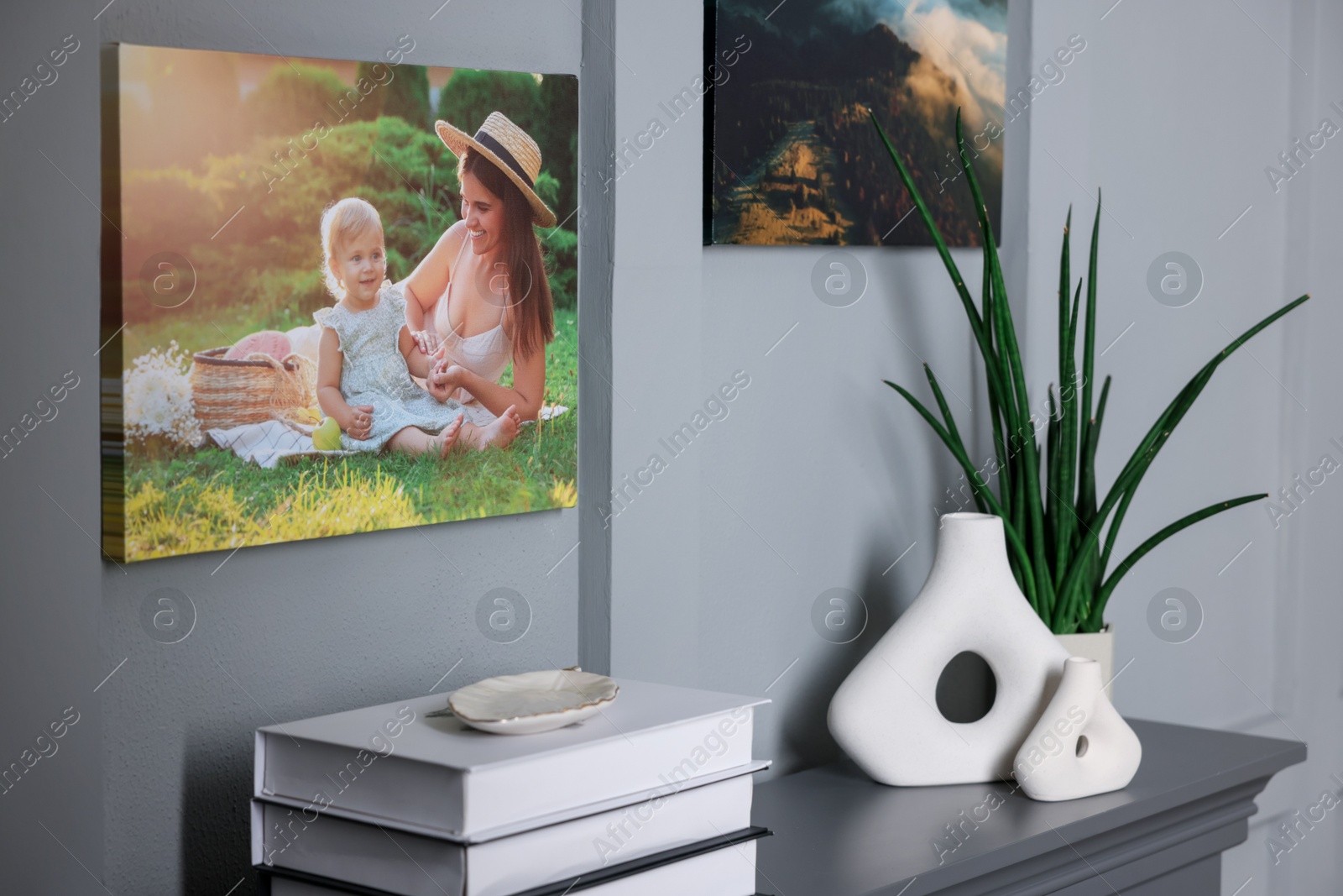 Photo of Canvas with printed photos on wall over decorative fireplace indoors