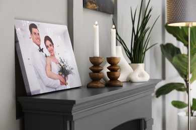 Photo of Canvas with printed photo and decor on fireplace indoors