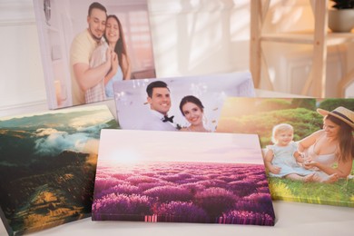 Photo of Canvas with different printed photos on table, closeup