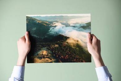 Photo of Canvas print. Woman with photo on light green background, closeup