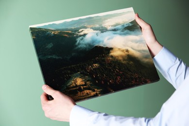 Photo of Canvas print. Woman with photo on light green background, closeup