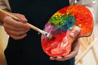 Photo of Man with palette and paintbrush indoors, closeup