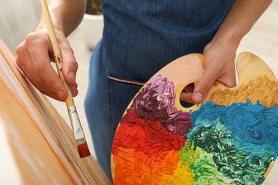 Photo of Man with palette and paintbrush drawing picture, closeup